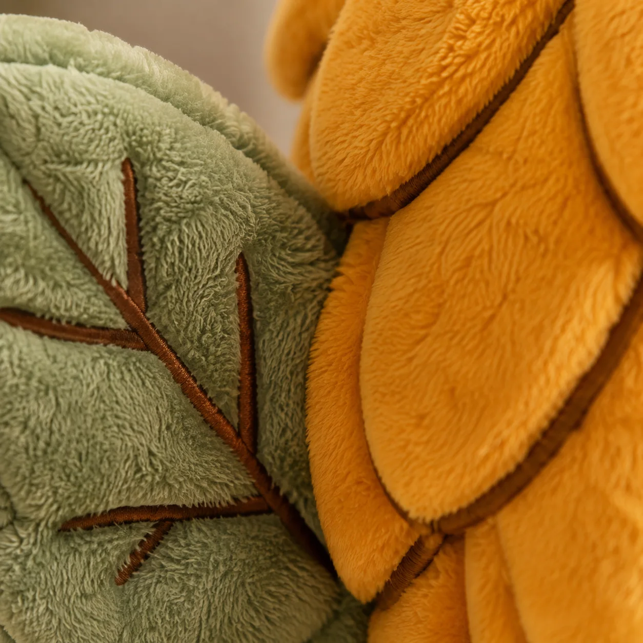 Macro detail of Hopper's sage wing embroidery and golden plush leaf texture